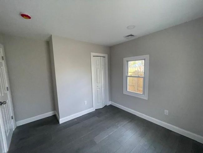 Unfurnished bedroom with a closet, baseboards, dark wood-style flooring, and visible vents | Image 8