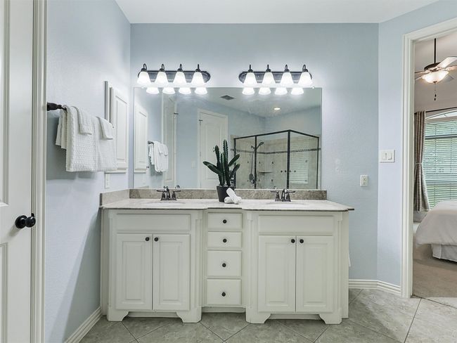 Ensuite bathroom featuring a shower stall, double vanity, tile patterned flooring, and ceiling fan | Image 22