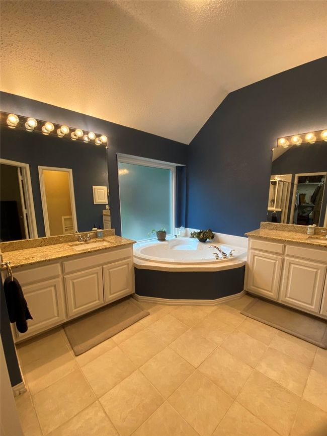 Full bathroom featuring a textured ceiling, tile patterned flooring, a garden tub, vanity, and vaulted ceiling | Image 22
