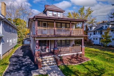 View of front facade with a garage, a porch, a front lawn, and a balcony | Image 1