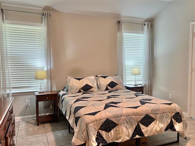 The primary suite is bathed in natural light through two large windows. | Image 11