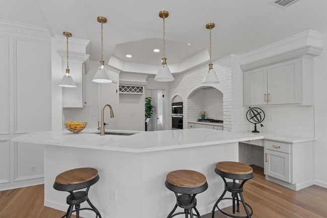 Kitchen featuring a sink, decorative backsplash, a breakfast bar, light stone countertops, and light wood finished floors | Image 8