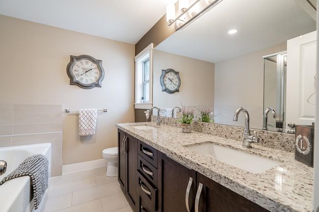 Bathroom featuring double vanity, a bath, toilet, tile patterned floors, and a shower with door | Image 19