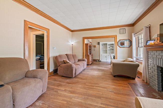 Living room featuring crown molding, a fireplace, light wood-style floors, and baseboards | Image 23