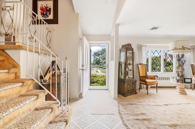 Carpeted foyer with stairway and radiator heating unit | Image 7