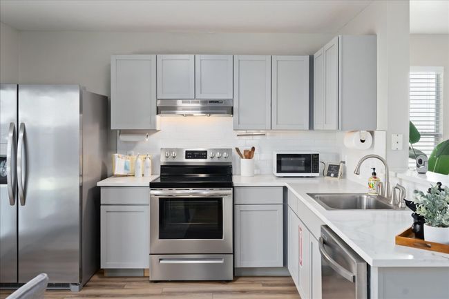 Kitchen with under cabinet range hood, gray cabinetry, appliances with stainless steel finishes, and a sink | Image 13