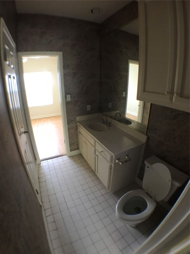 Bathroom featuring toilet, wallpapered walls, vanity, baseboards, and tile patterned flooring | Image 6