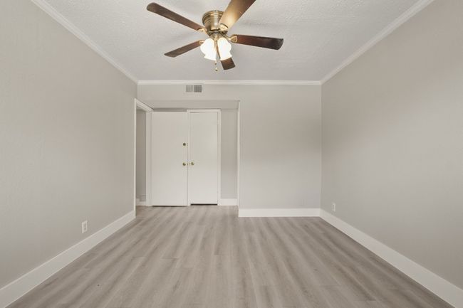 Spare room featuring light wood-style floors, a ceiling fan, ornamental molding, and a textured ceiling | Image 24