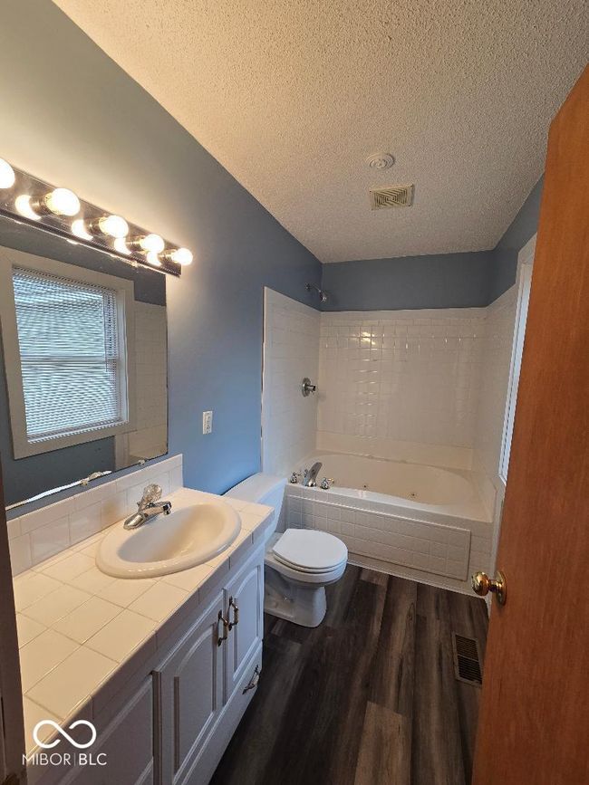 bathroom with visible vents, toilet, a textured ceiling, wood finished floors, and vanity | Image 28