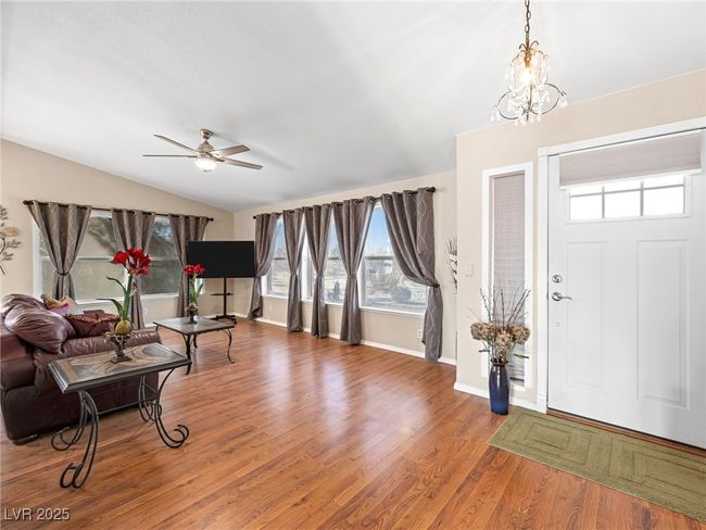 Foyer with ceiling fan with notable chandelier, lofted ceiling, wood finished floors, and baseboards | Image 15