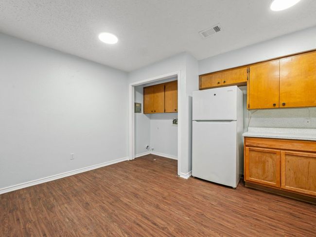 Kitchen with freestanding refrigerator, dark wood finished floors, light countertops, and brown cabinets | Image 5
