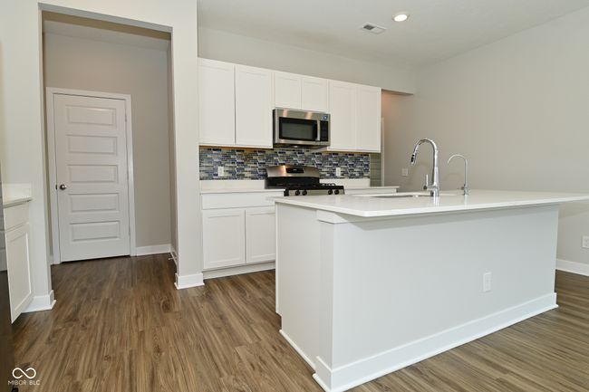 kitchen with decorative backsplash, white cabinetry, a sink, and appliances with stainless steel finishes | Image 15