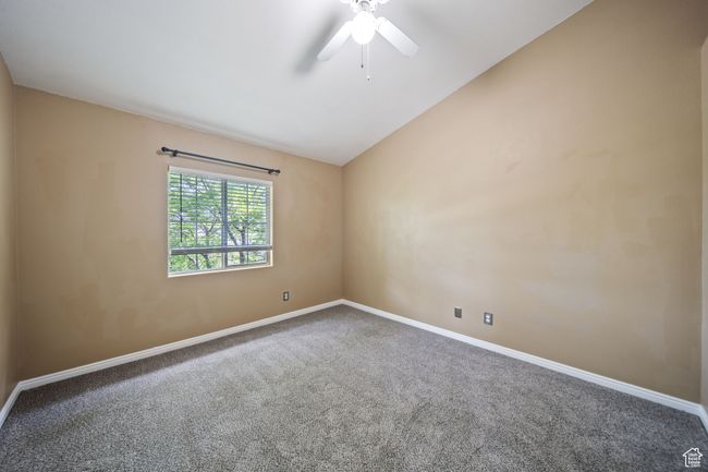 Carpeted spare room featuring vaulted ceiling and ceiling fan | Image 23