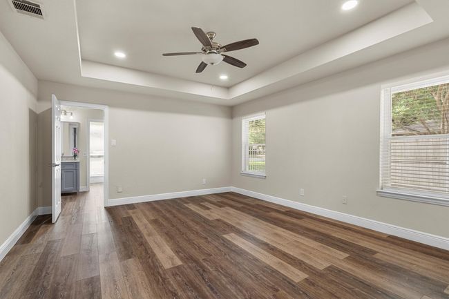The spacious primary bedroom has a tray ceiling and is privately split from the other bedrooms. | Image 20