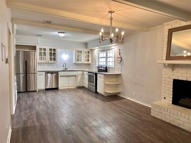 Kitchen with appliances with stainless steel finishes, beamed ceiling, dark wood-style floors, open shelves, and a chandelier | Image 12