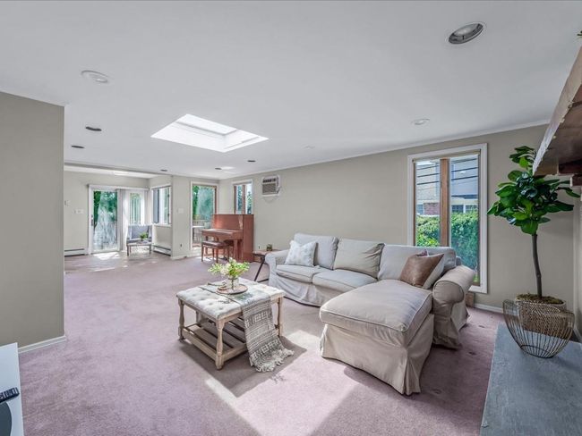 Living area with baseboards, a healthy amount of sunlight, a skylight, and light carpet | Image 14