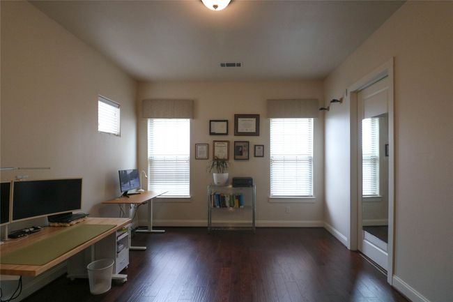 Office area with dark wood-style flooring, visible vents, and baseboards | Image 24