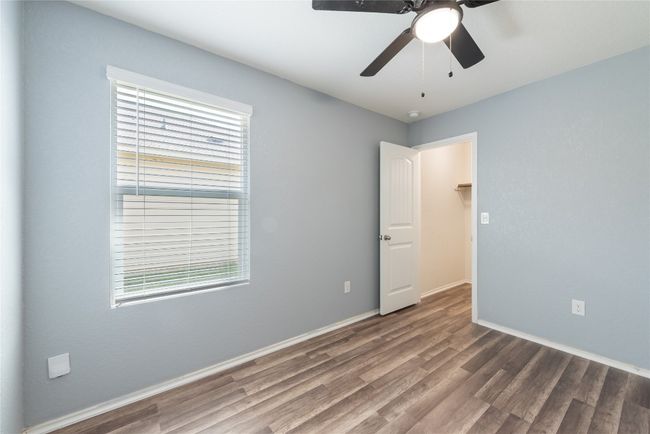 Unfurnished bedroom featuring multiple windows, wood finished floors, and a ceiling fan | Image 17