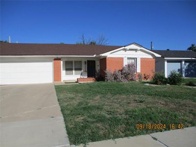 Single story home featuring a front yard and a garage | Image 1