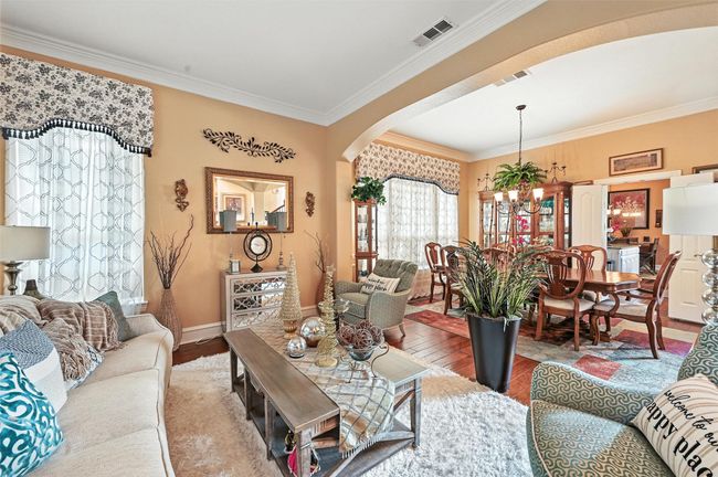 Living area featuring a chandelier, arched walkways, wood finished floors, and crown molding | Image 4