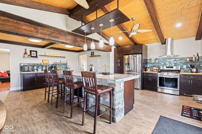 Recently remolded kitchen with steel appliances, decorative backsplash, and a breakfast bar area | Image 13