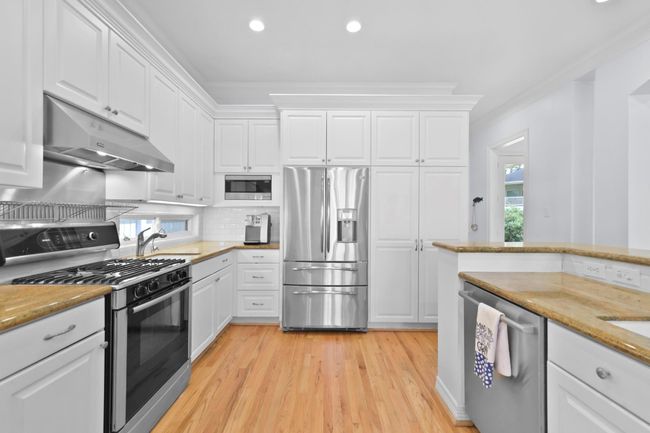 This side of the kitchen features a sleek refrigerator, built-in microwave, and ample storage. | Image 21