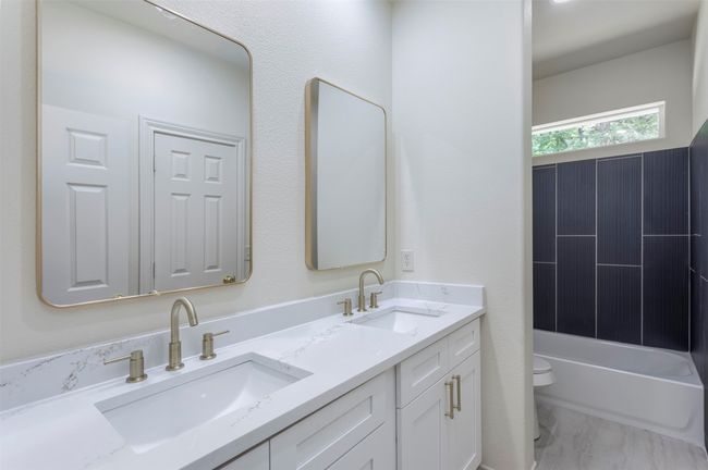 Full bath featuring toilet, double vanity, a tub to relax in, marble finish floors, and a shower | Image 24