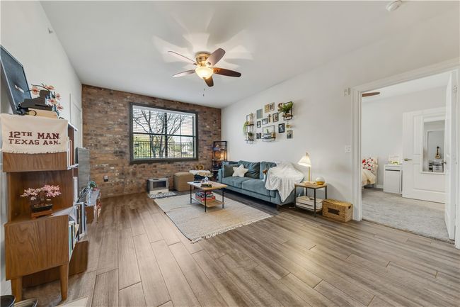 Living room featuring wood-type flooring, ceiling fan, and brick wall | Image 10