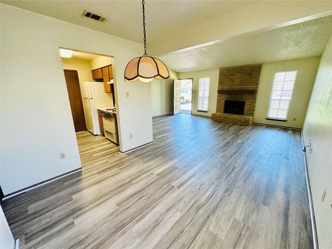 Unfurnished living room with a textured ceiling, light wood-type flooring, and a fireplace | Image 8