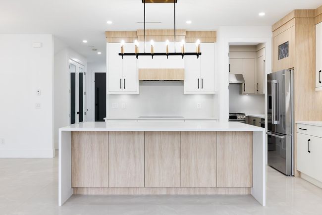 Kitchen featuring high end appliances, a spacious island, light countertops, light brown cabinets, and recessed lighting | Image 11