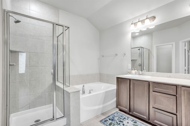 Bathroom featuring a garden tub, a stall shower, vanity, tile patterned floors, and lofted ceiling | Image 17