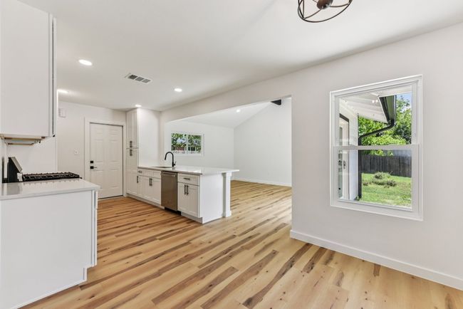 Kitchen with a peninsula, white cabinetry, open floor plan, light wood finished floors, and recessed lighting | Image 8