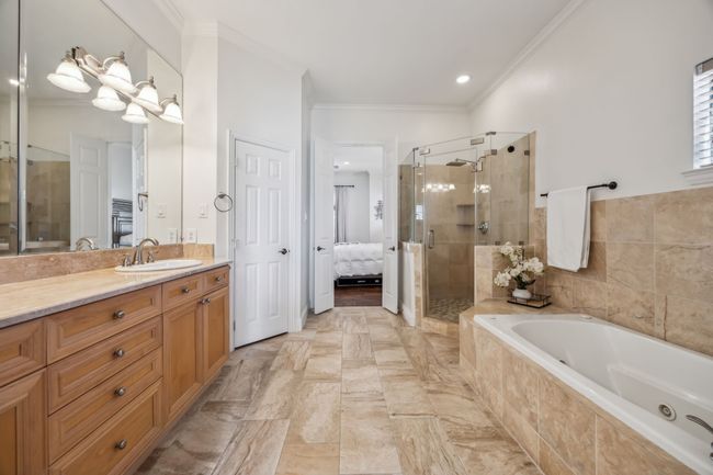Spa-like bath featuring dual sinks, separate shower, soaking tub, and large walk-in closet. | Image 21