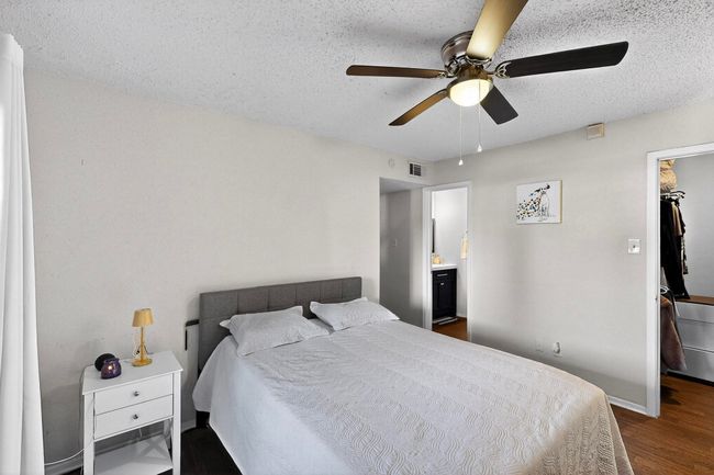 Bedroom featuring a walk in closet, dark wood-style flooring, a textured ceiling, ceiling fan, and a closet | Image 10