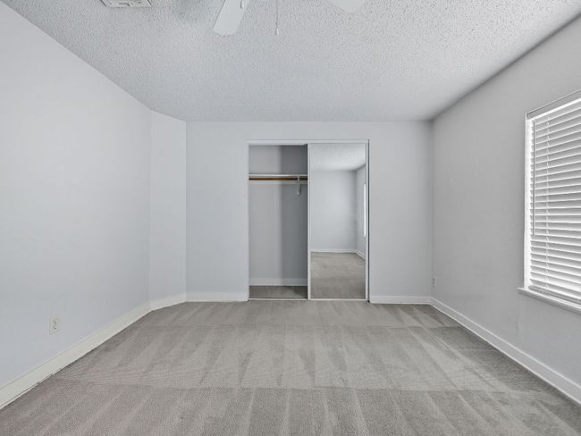 Unfurnished bedroom with light colored carpet, a textured ceiling, a closet, and a ceiling fan | Image 24