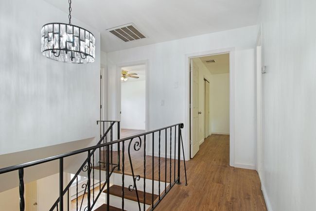 Corridor with an upstairs landing, wood finished floors, baseboards, and a chandelier | Image 17