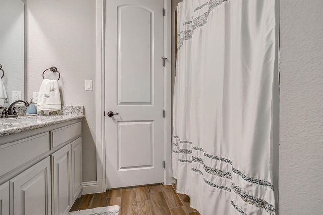 Bathroom featuring vanity, wood finished floors, a textured wall, and curtained shower | Image 24