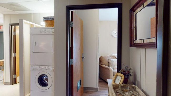 Washroom with stacked washer / dryer, wood finished floors, and baseboards | Image 26