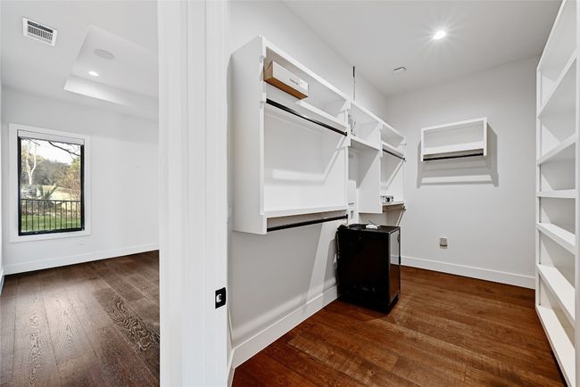 Walk in closet with visible vents, a raised ceiling, and dark wood-style floors | Image 21
