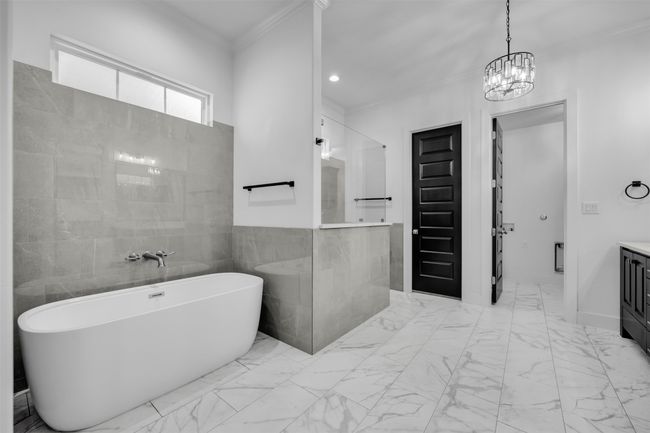 Bathroom with marble finish floor, a freestanding bath, crown molding, and vanity | Image 13