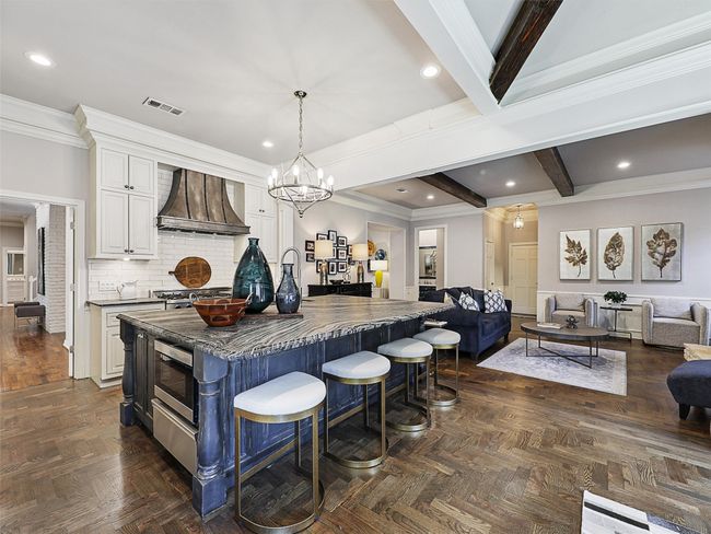 Kitchen featuring premium range hood, open floor plan, white cabinets, a breakfast bar, and stainless steel microwave | Image 4