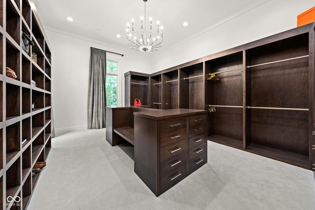 primary walk in closet featuring light colored carpet and a chandelier | Image 36