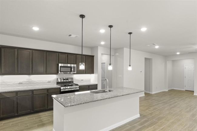 Kitchen featuring wood finish floors, dark brown cabinetry, visible vents, a sink, and stainless steel appliances | Image 13