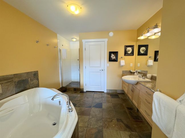 Bathroom with stone tile flooring, a bath, a stall shower, and vanity | Image 22