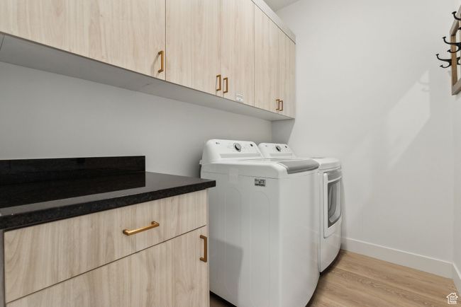 Laundry room featuring cabinets, separate washer and dryer, and light hardwood / wood-style floors | Image 26