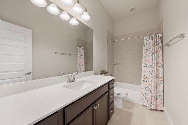 Bathroom with vanity, toilet, shower / bath combo with shower curtain, tile patterned flooring, and baseboards | Image 27