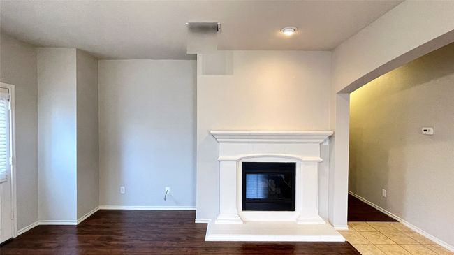 Unfurnished living room with a glass covered fireplace and wood finished floors | Image 14