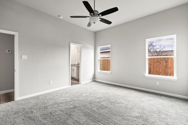 Unfurnished bedroom featuring dark colored carpet, ensuite bathroom, and ceiling fan | Image 14