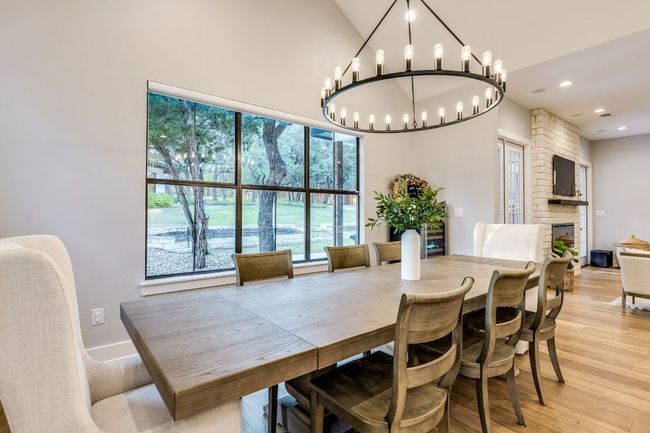 This dining area features a large wagon wheel chandelier and picturesque views of the backyard. | Image 14