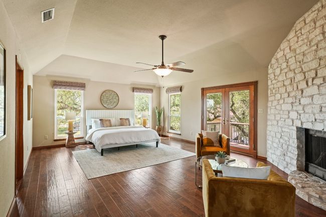 Bedroom with access to outside, lofted ceiling, dark wood-style floors, a fireplace, and french doors | Image 9